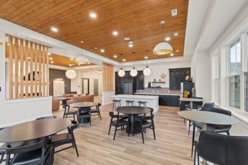 a community room with tables and chairs and a kitchen at Hadley Place Apartments, Enola